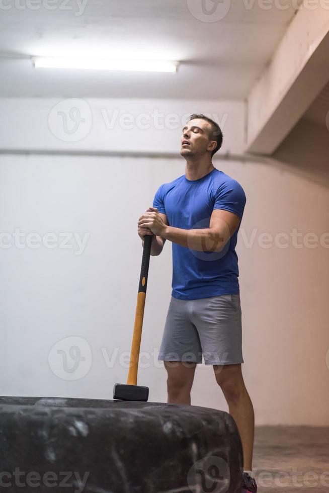 man workout with hammer and tractor tire photo