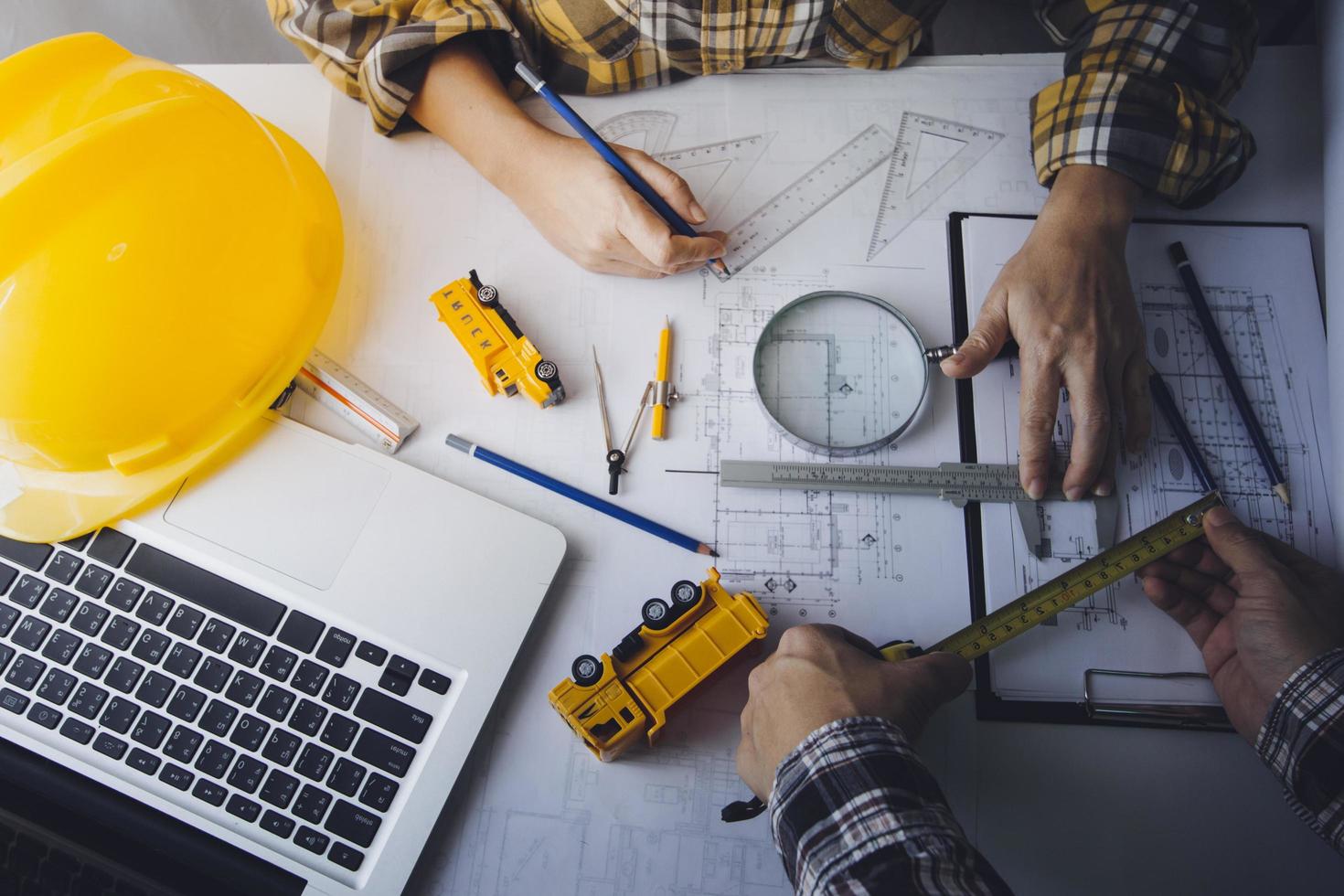 Two colleagues discussing data working and tablet, laptop with on on architectural project at construction site at desk in office photo