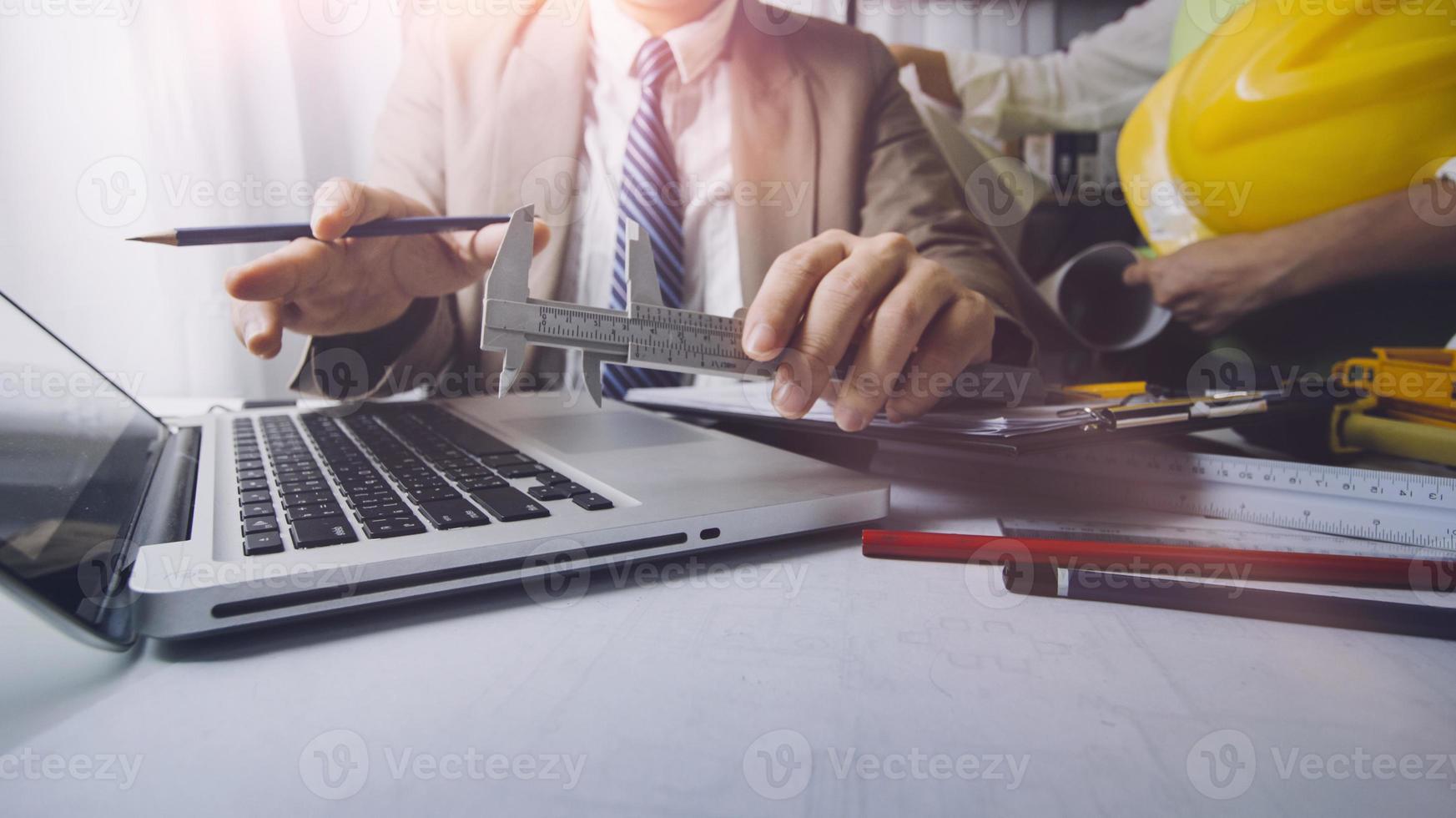 business hand working and laptop with on on architectural project at construction site at office desk in office photo
