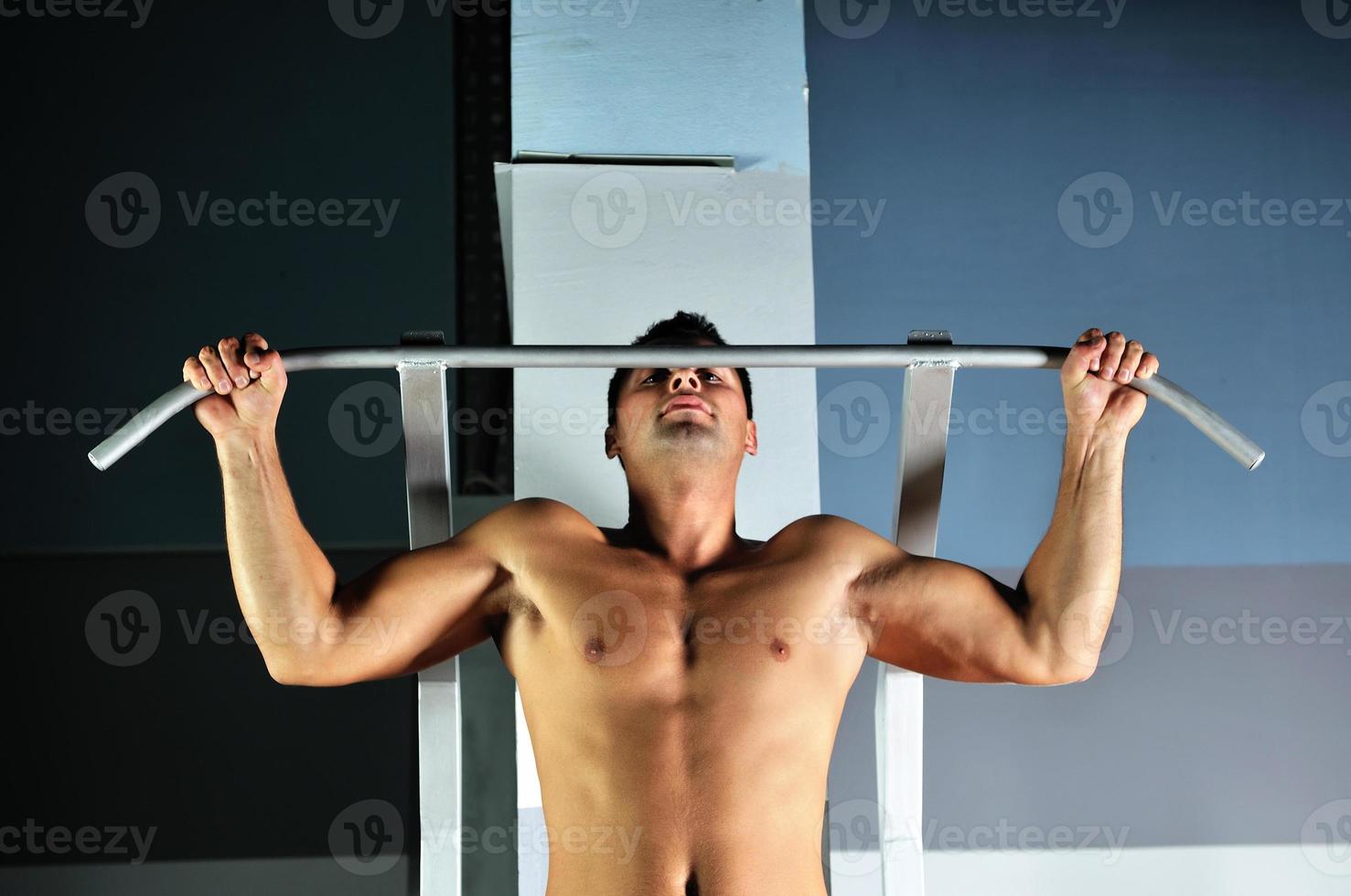 young man with strong arms working out in gym photo