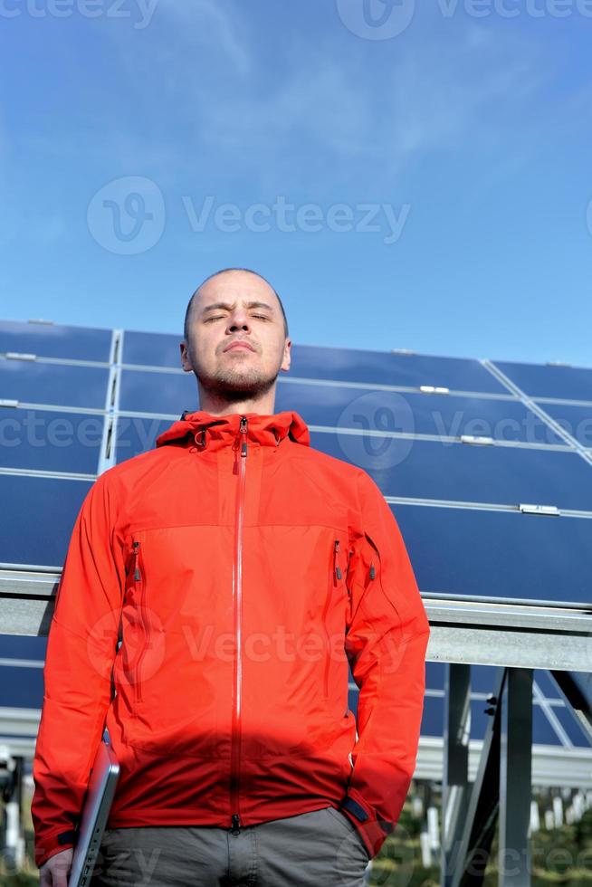 engineer using laptop at solar panels plant field photo