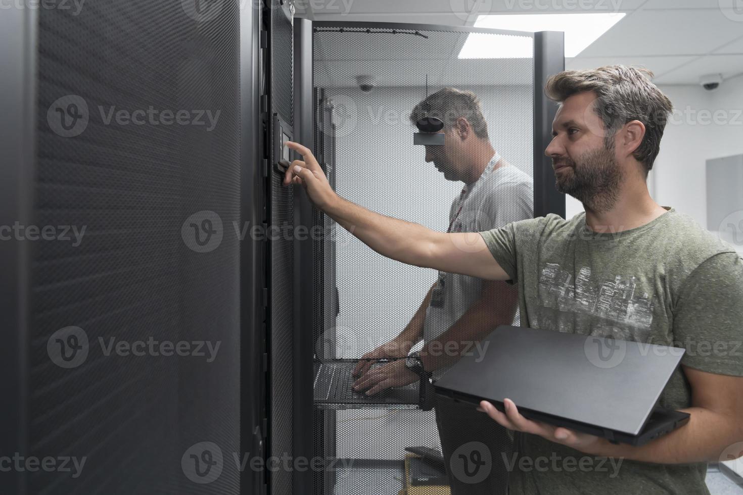 Technicians team updating hardware inspecting system performance in super computer server room or cryptocurrency mining farm. photo