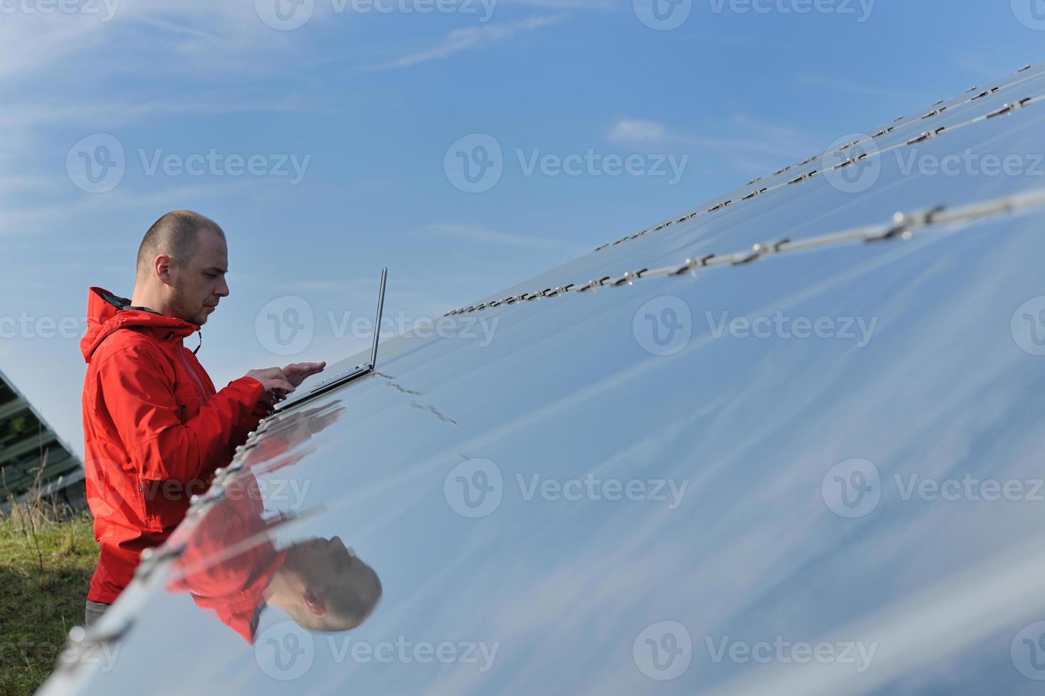 engineer using laptop at solar panels plant field photo