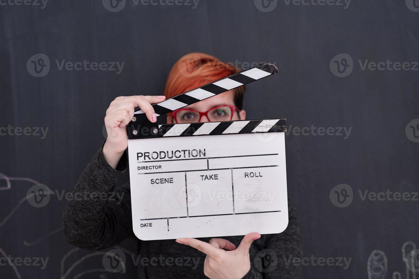 redhead woman holding clapper on black background photo