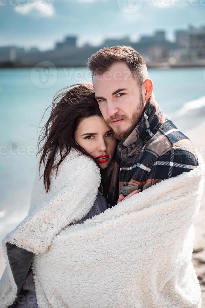 Couple is standing on the beach, posing for the camera photo