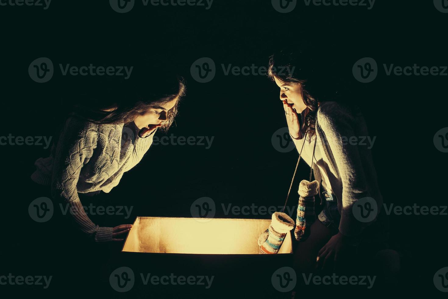 las hermanas abren una caja con un regalo de navidad y miran fascinadas dentro foto