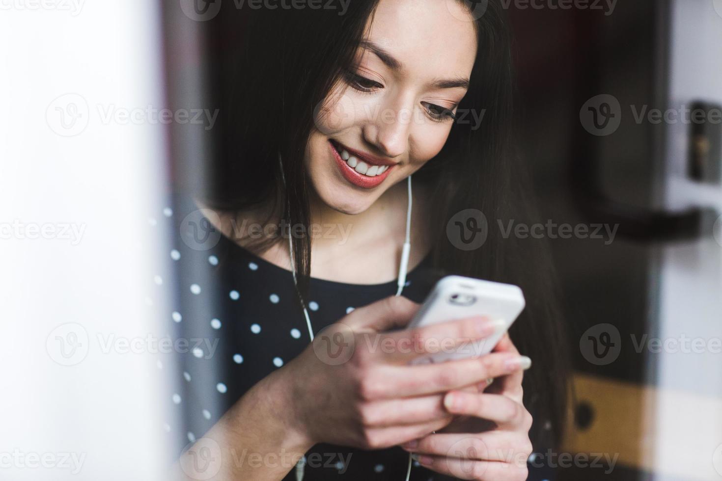 hermosa chica escuchando música en el teléfono con auriculares foto