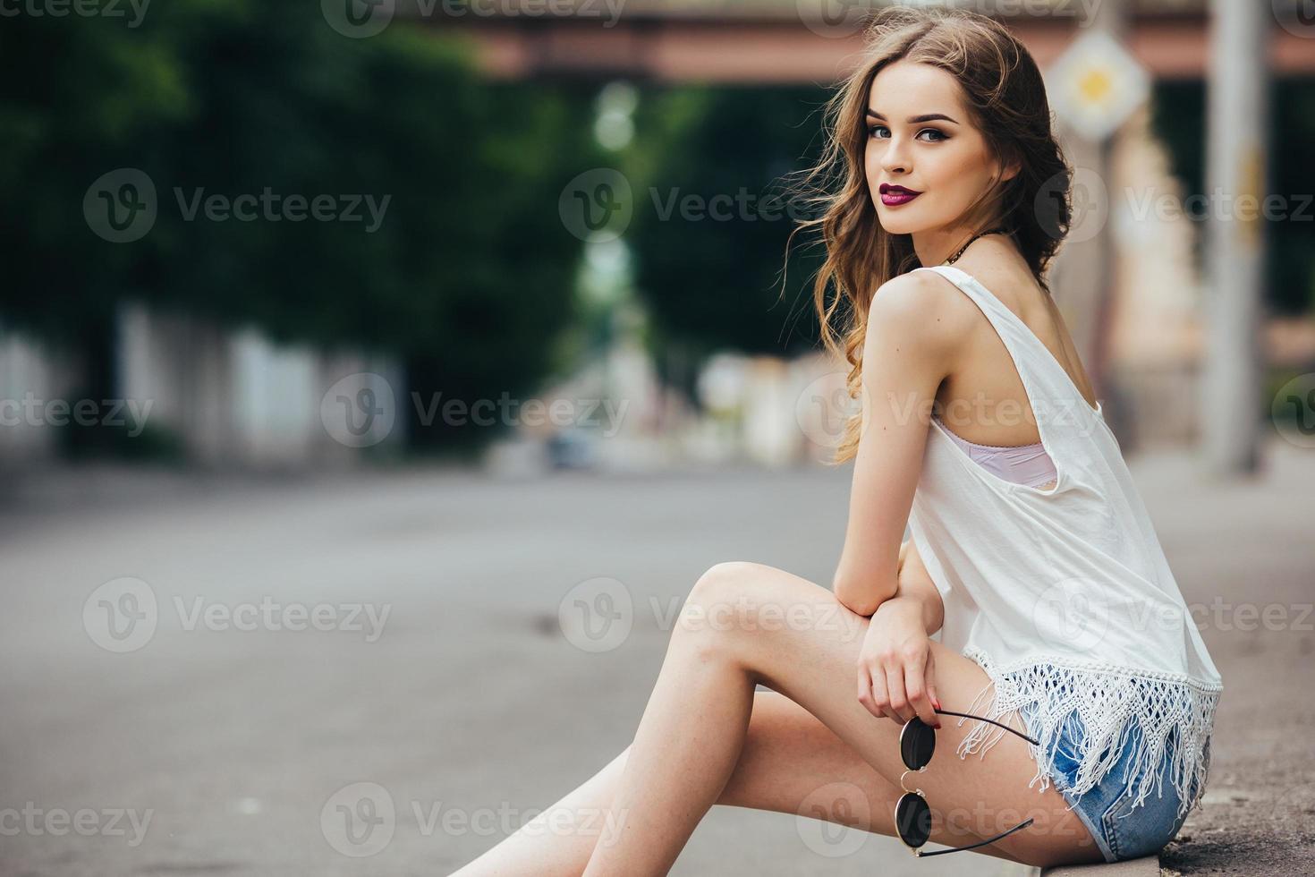 niña bonita sentada en una calle de la ciudad foto