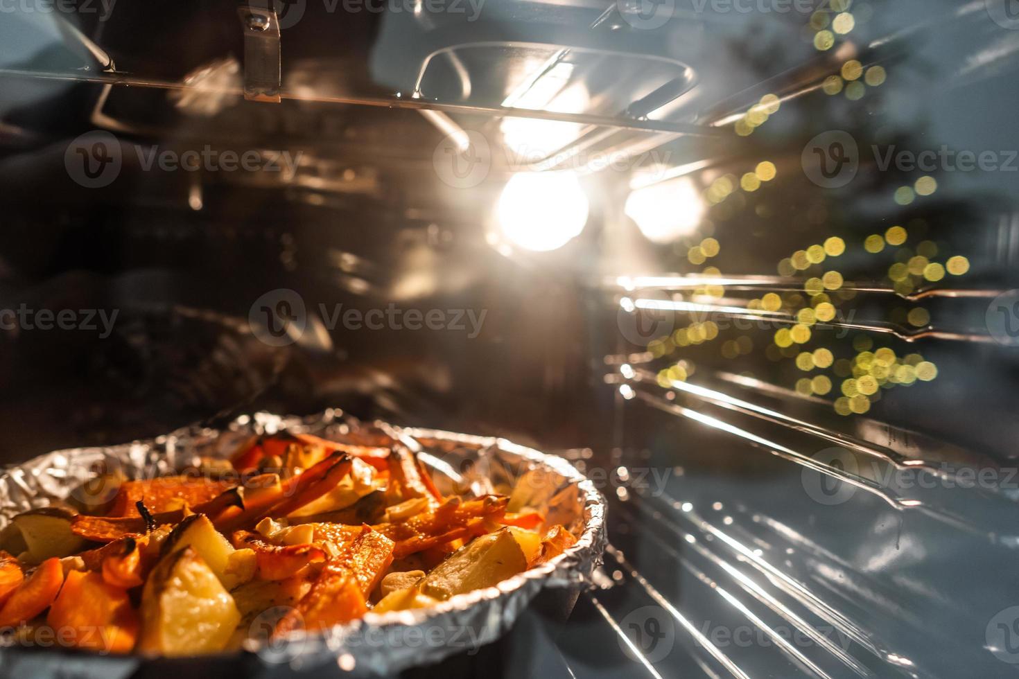 Baked potatoes with carrot and other spices in roasting pan. photo