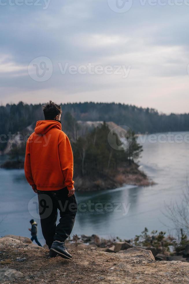 A young man standing on the edge of a cliff poses for the camera photo