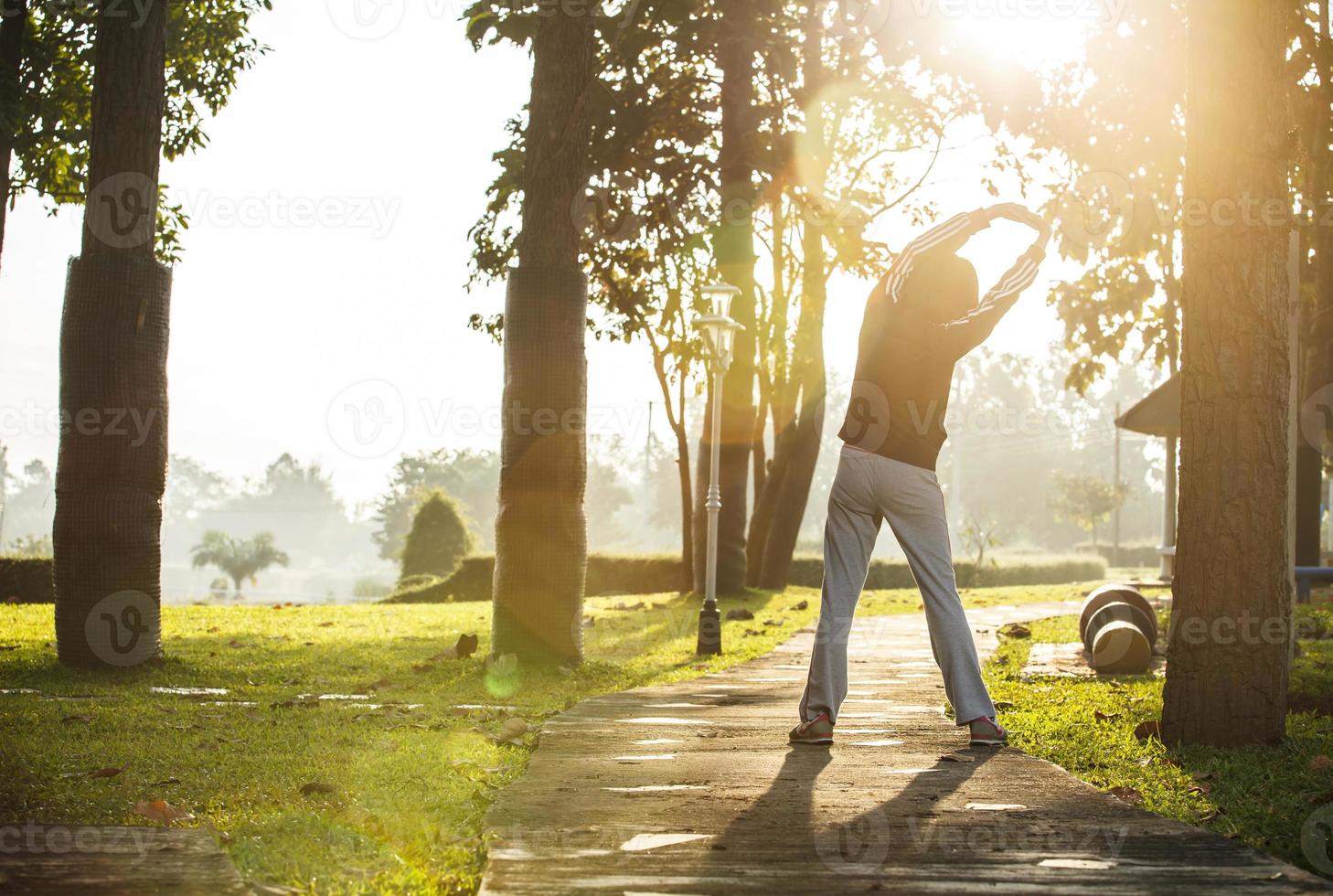 Asian woman jogging in park with cloudy sky and lens flare photo