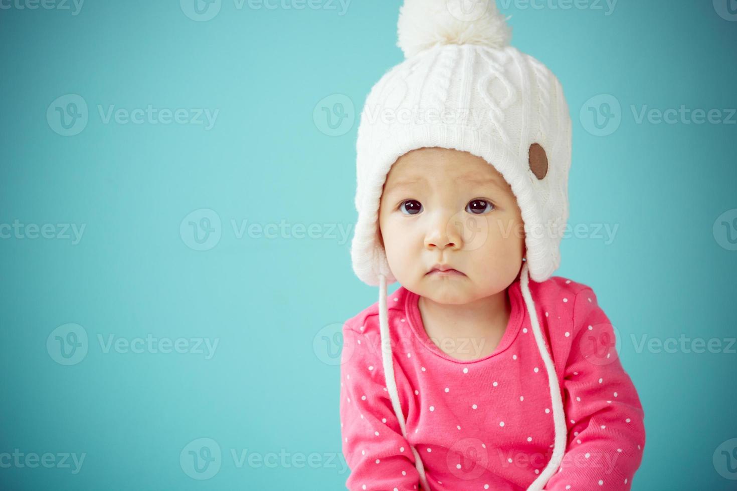 Little baby in knit winter clothing closing face with knitted beanie photo