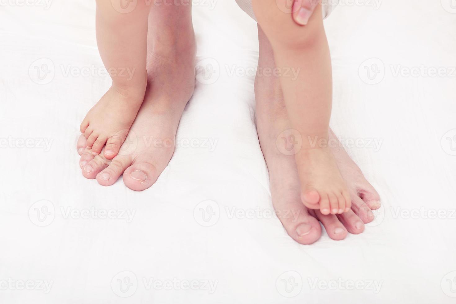 First steps. Baby learning to walk, with help of mothers and fathers photo