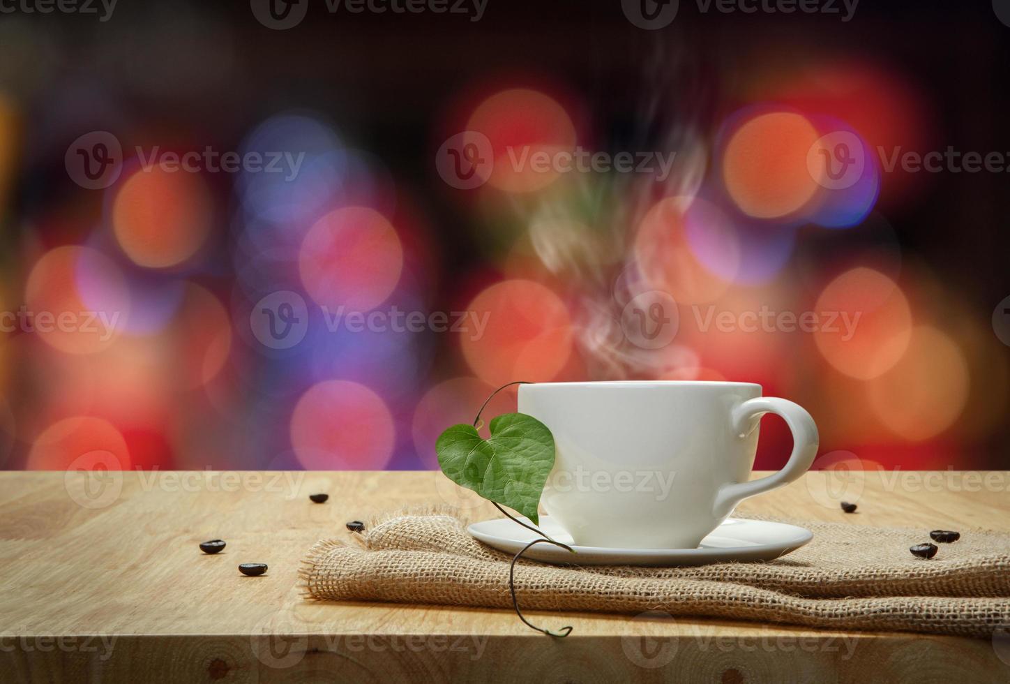 White cup of Espresso with sacking on the wooden table and the bokeh background photo