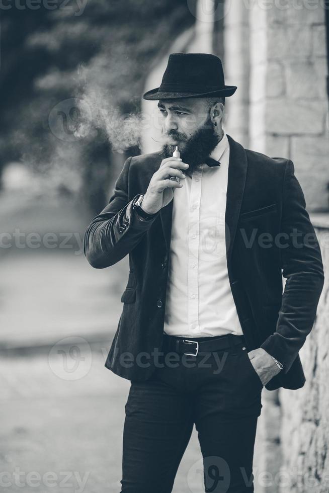 un hombre rico con barba fuma un cigarrillo electrónico foto
