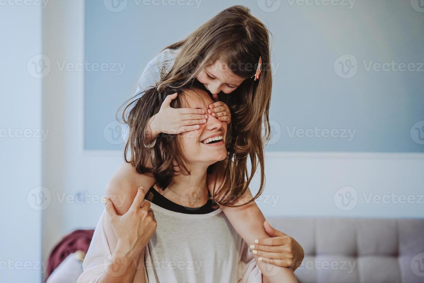 beautiful little daughter piggybacking on her happy mother photo