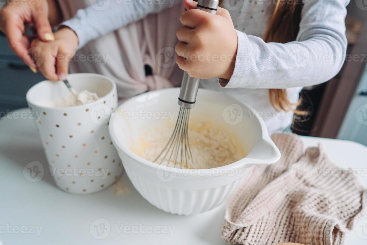 mom teaches her little daughter to cook food photo