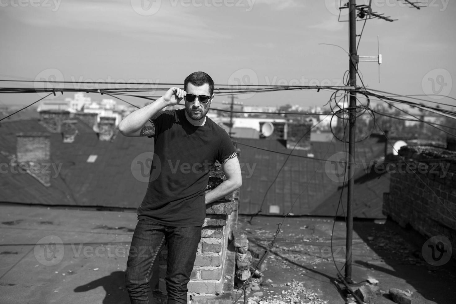 El hombre de las botas auténticas y el orillo de jeans en el techo del edificio en el casco antiguo foto