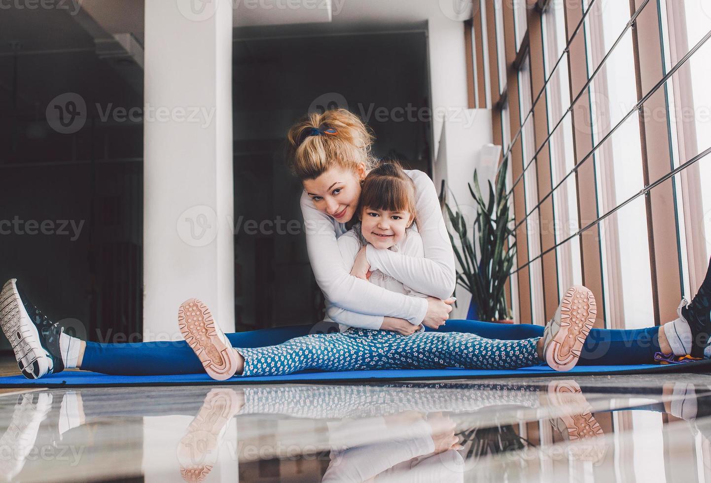 madre e hija se abrazan y se estiran en el gimnasio foto