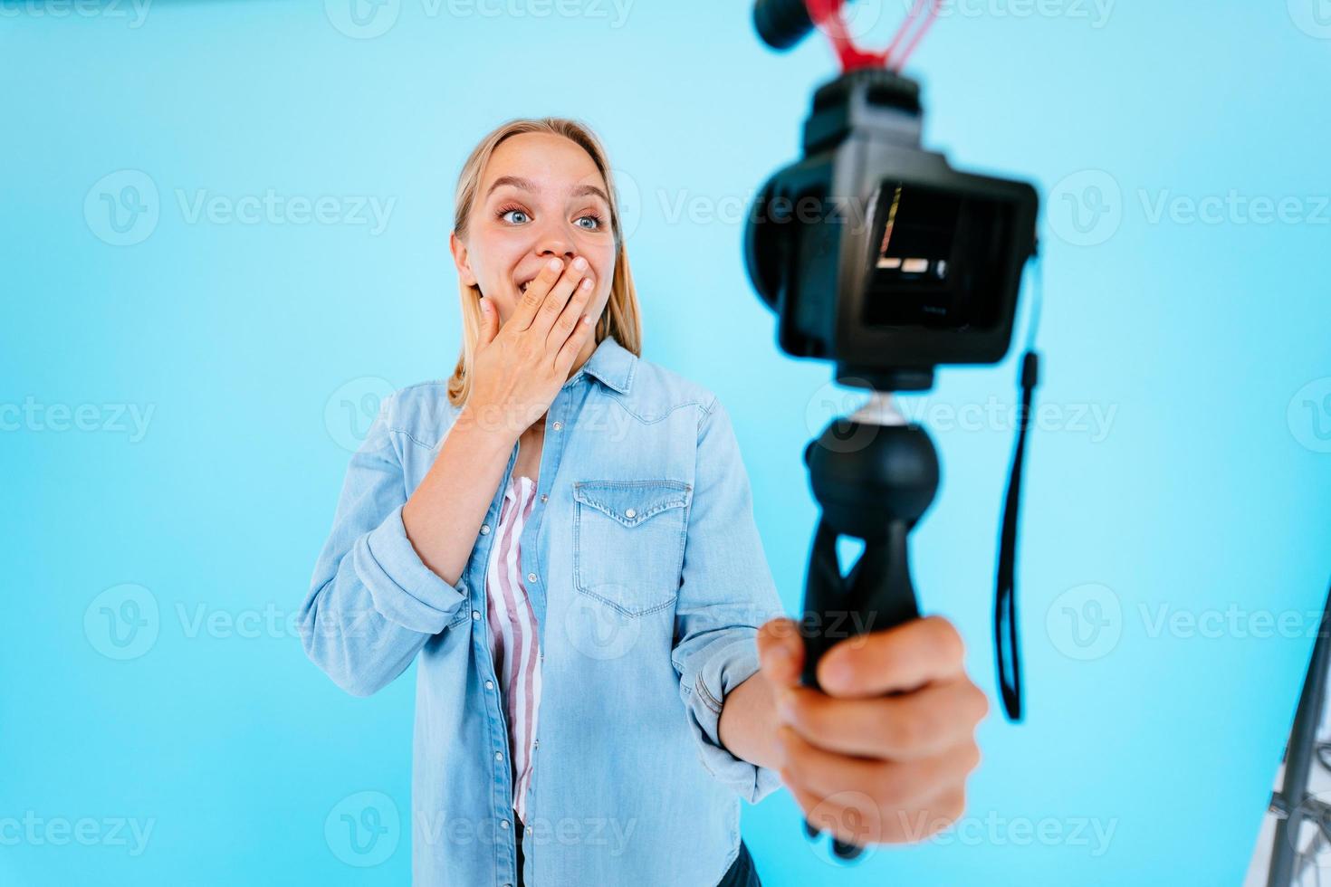 Beautiful girl blogger relieves itself at camera isolated blue background photo