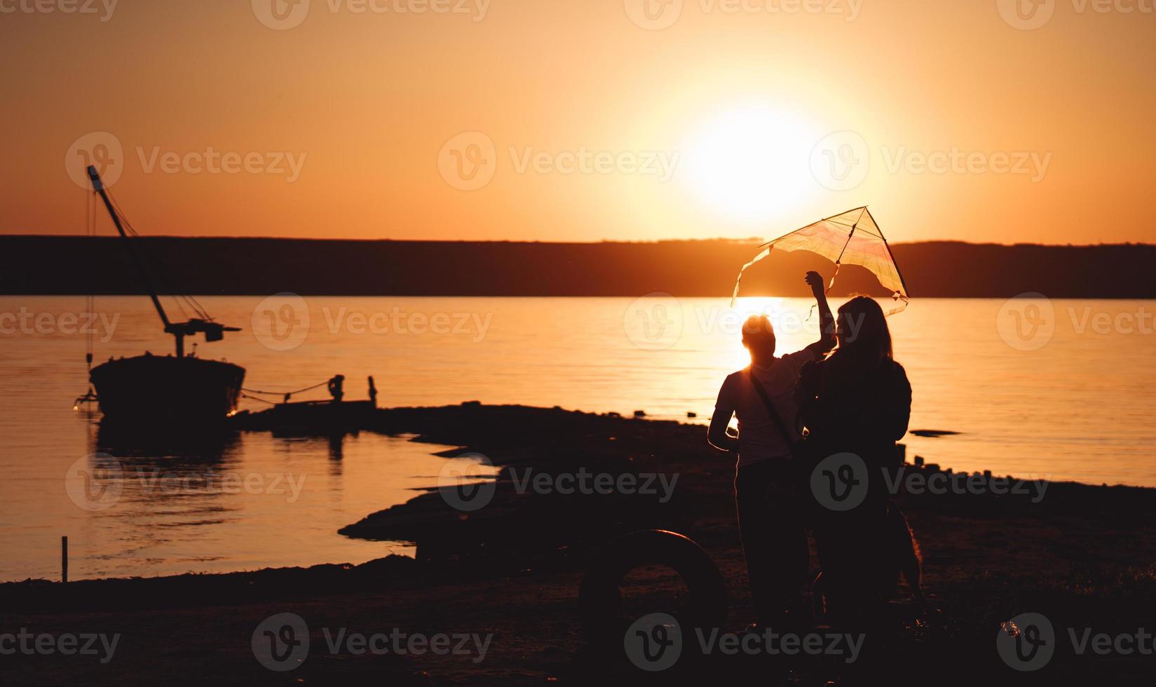 A young couple on the shore launches a kite photo