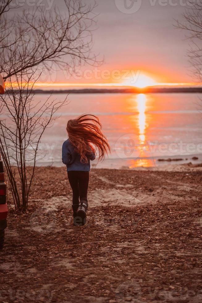 mujer disfrutando del tiempo relajándose junto al hermoso lago al amanecer. foto