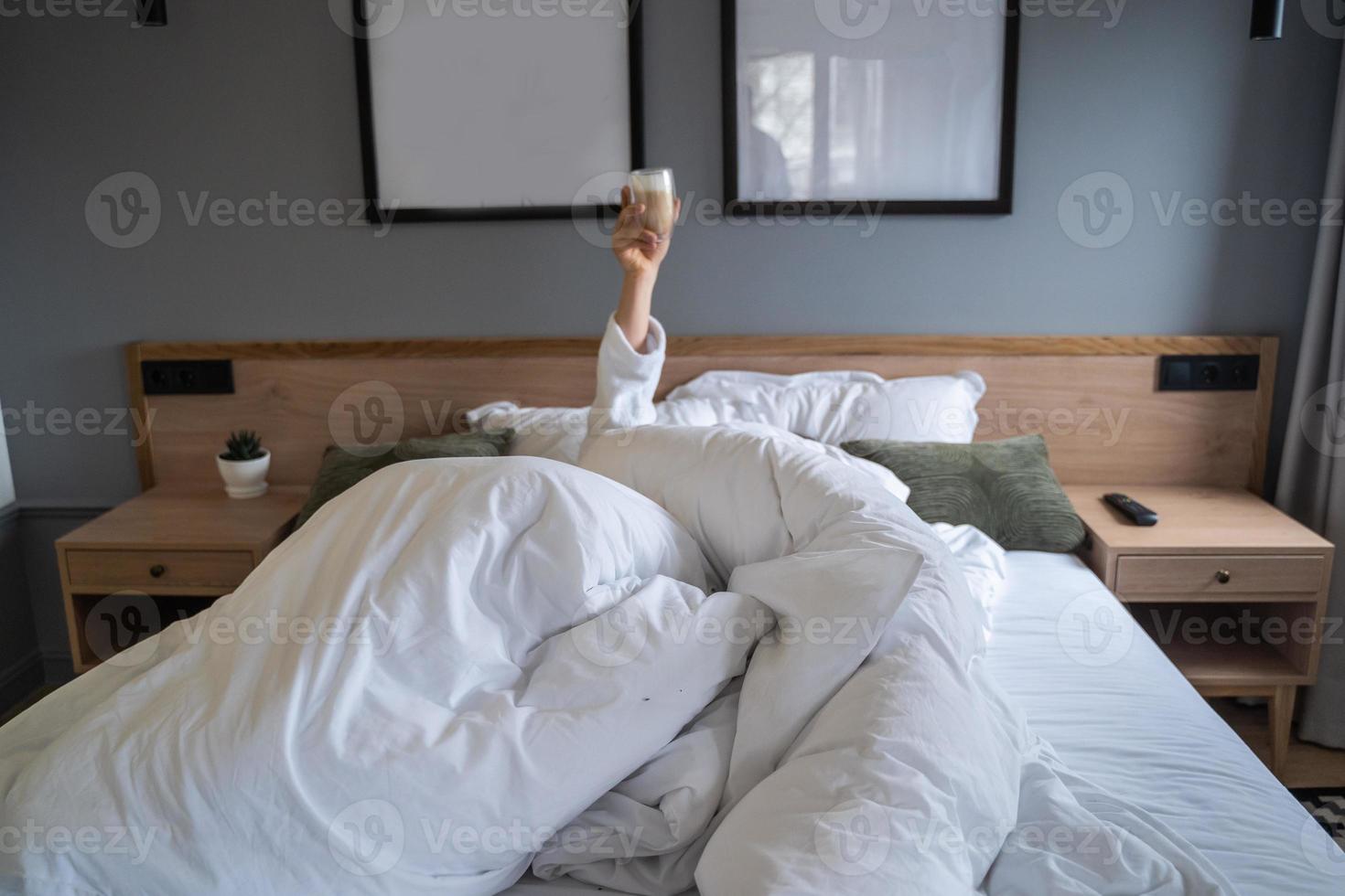 Hand holding a cup of coffee at home in bed photo