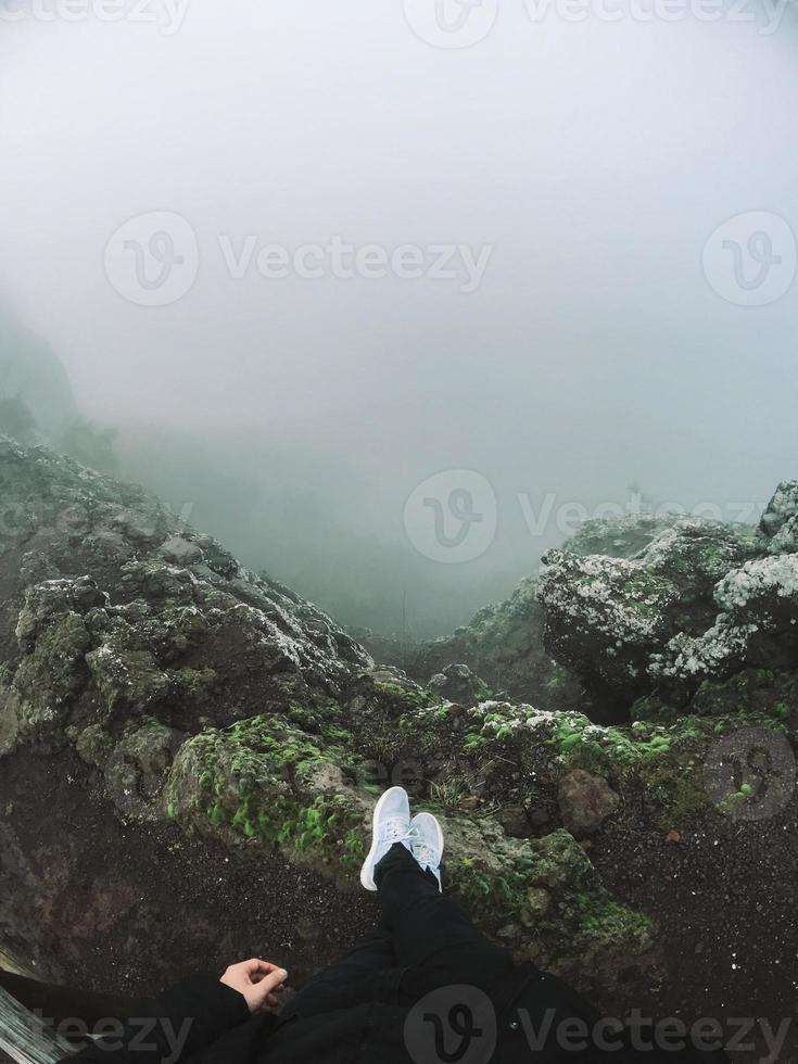 hombre en el acantilado mira la niebla foto