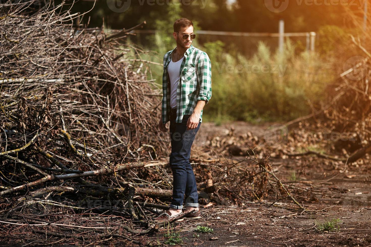 The man in the authentic boots and selvedge jeans  on a the background of branches photo
