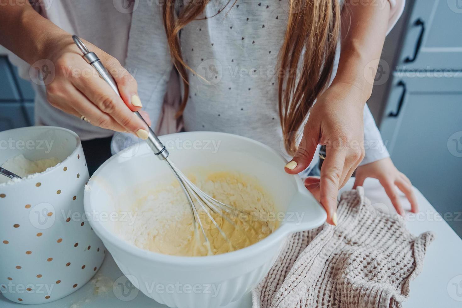 mom teaches her little daughter to cook food photo