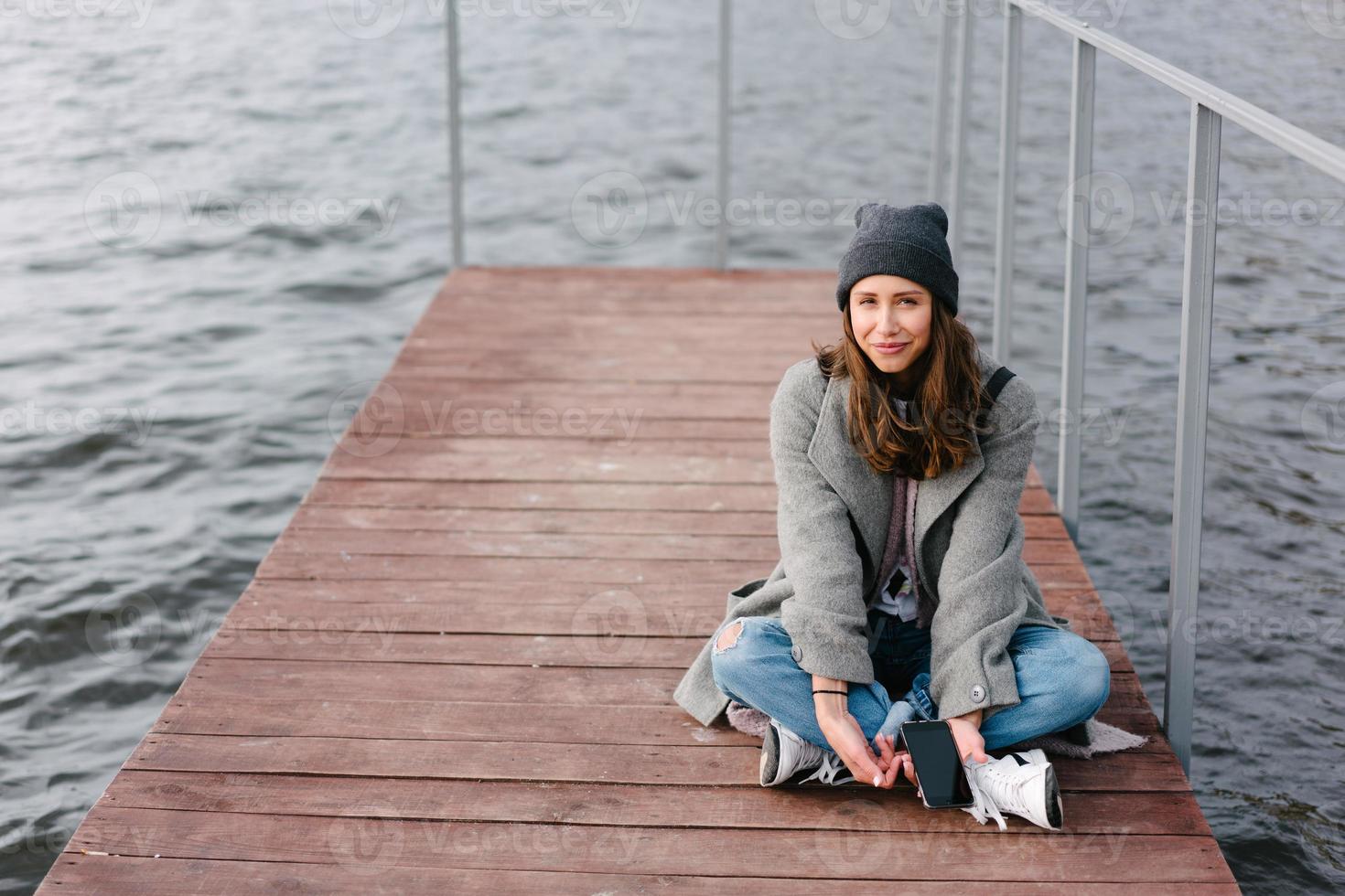 Young pretty girl on wooden bench on old pier photo