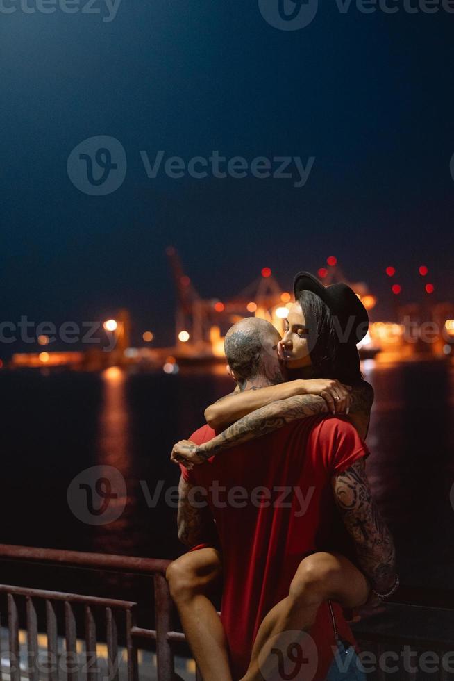 Guy and girl hugging each other on a background of the night port photo