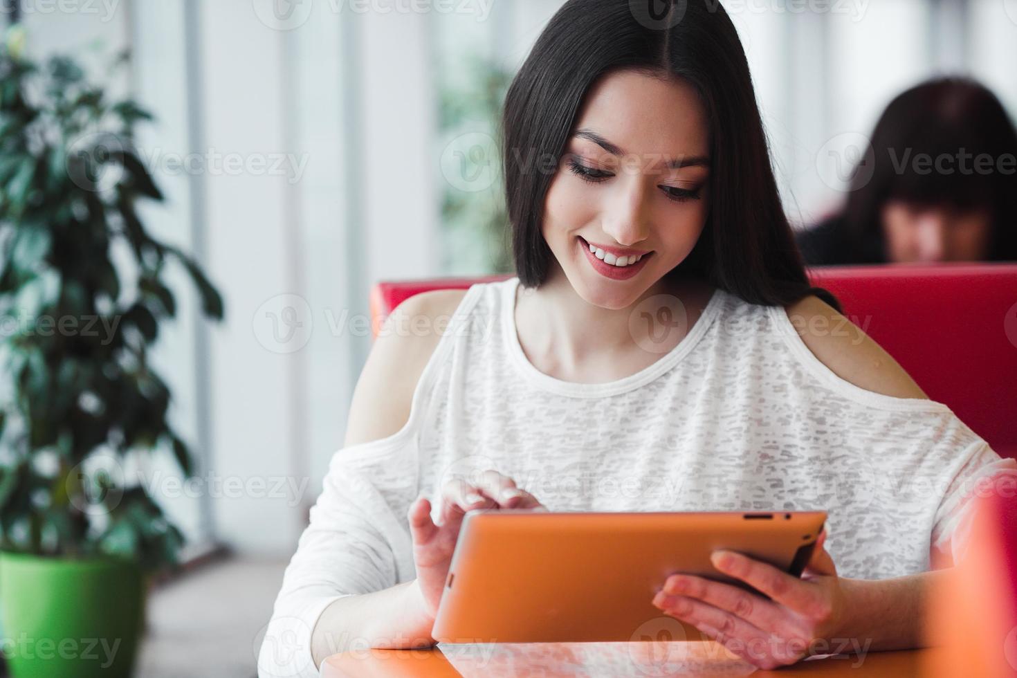 Beautiful girl working on a tablet and smiling photo
