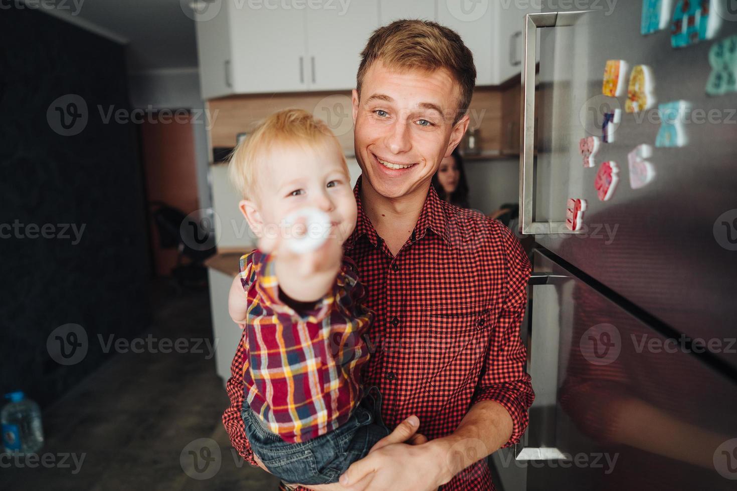 Dad and little son in the kitchen by the fridge photo