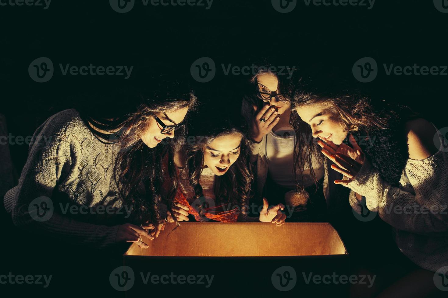 Sisters opens a box with a Christmas present and fascinated looks inside photo