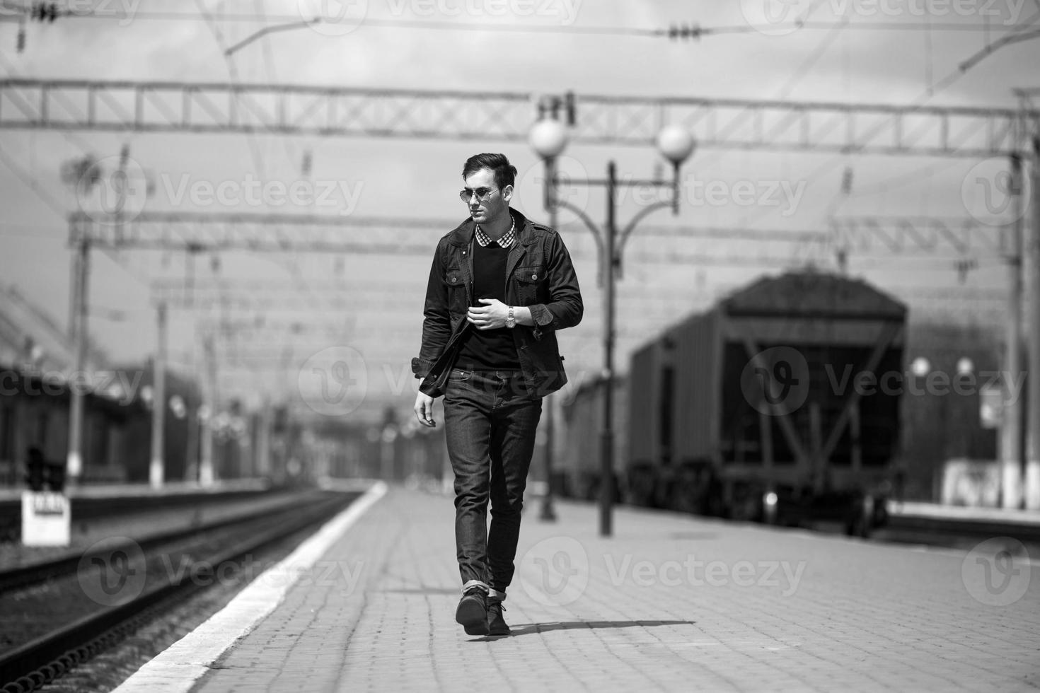 A man dressed in jeans on the background of the train and the station photo