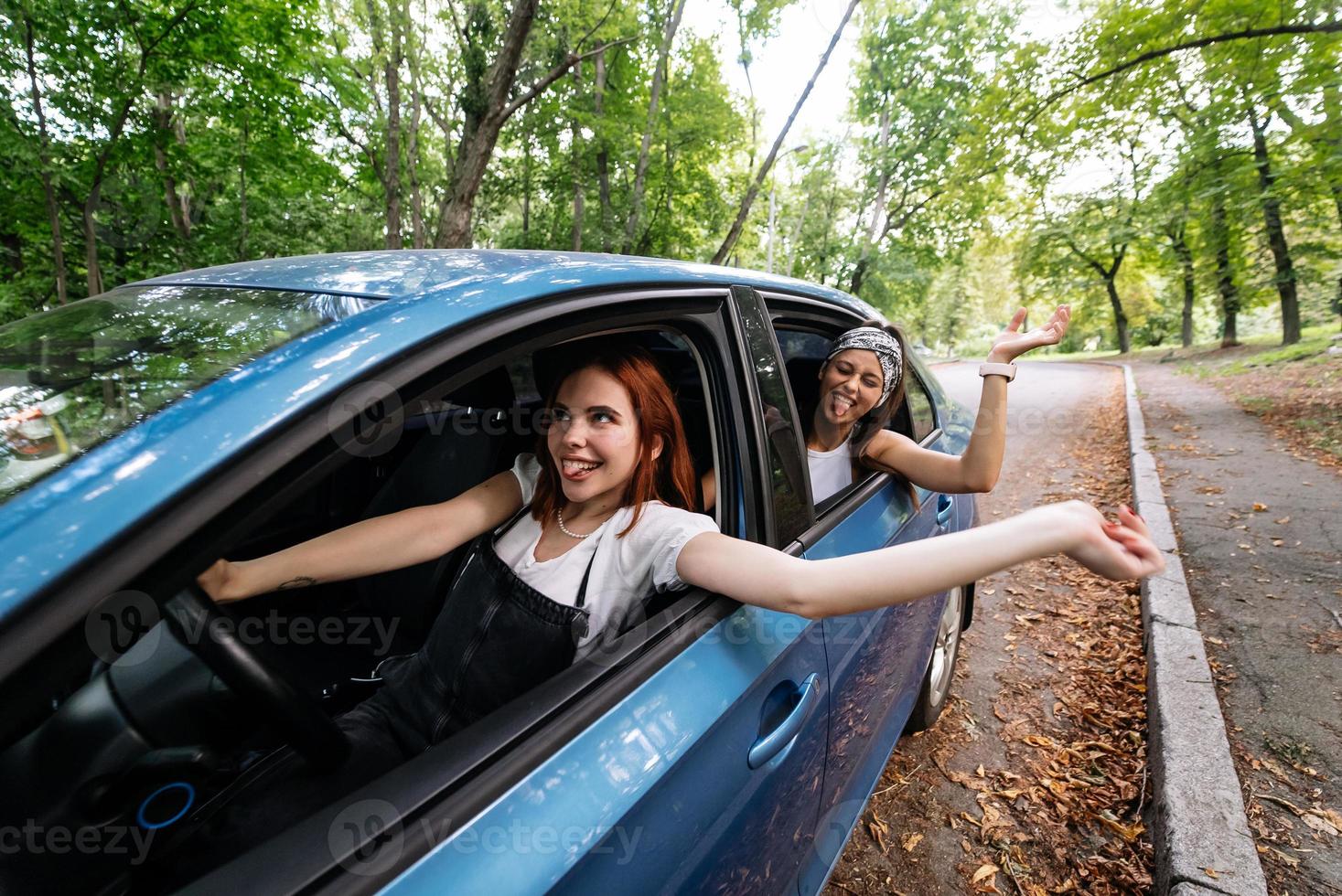 Two girlfriends fool around and laughing together in a car photo