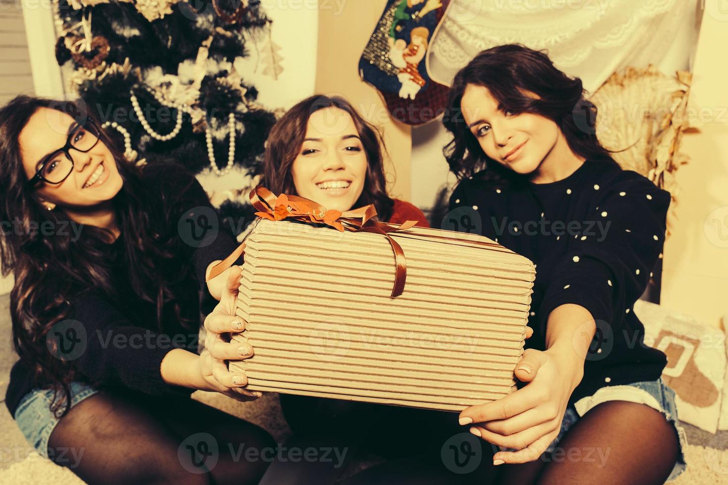 Beautiful girl shows Christmas gifts directly into the camera. Decorative vintage apartment. photo