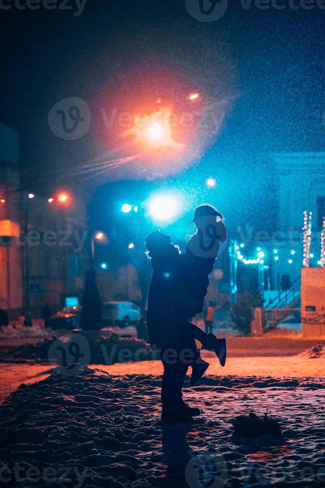 Young adult couple in each other's arms on snow covered street. photo