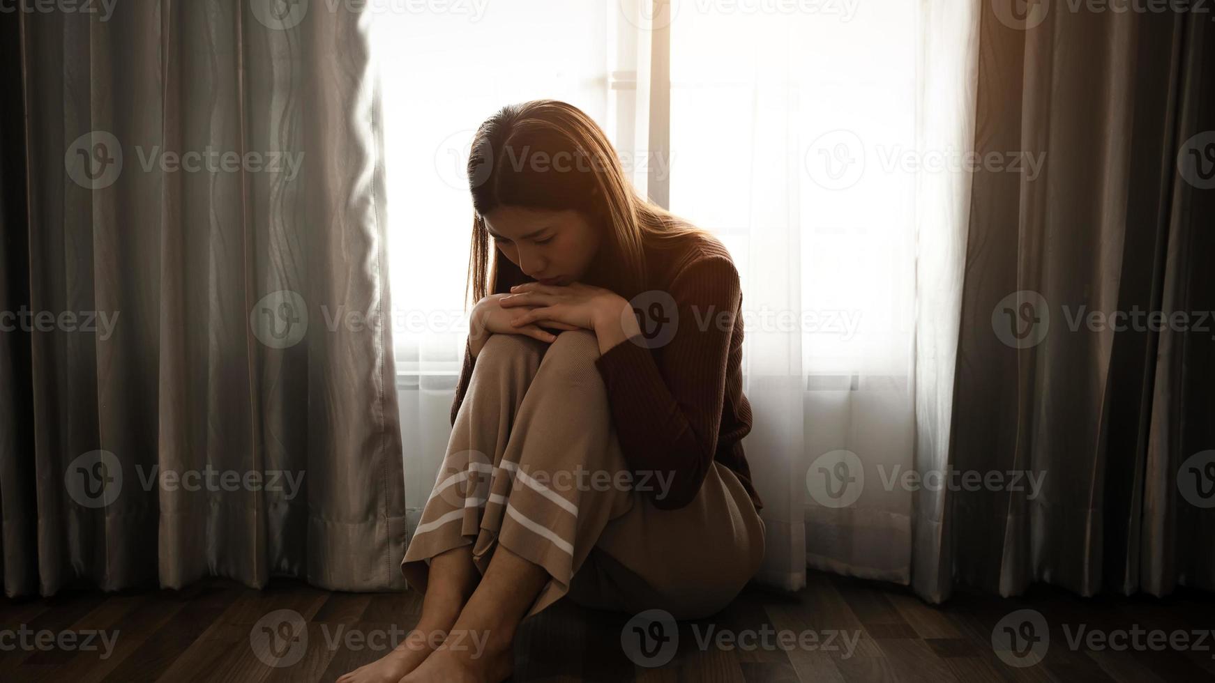 la mujer se sienta depresión de pie junto a la ventana y la ansiedad copia el espacio. foto