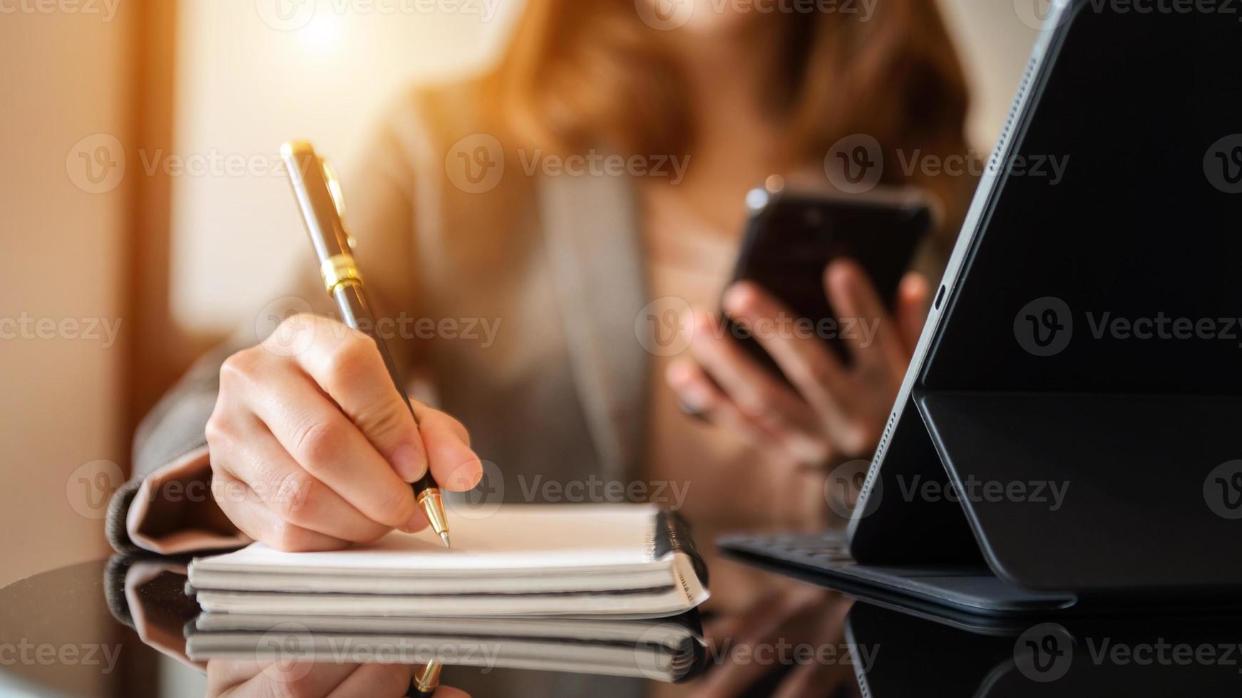 businesswoman hand writing on the notepad with new modern computer strategy diagram as concept morning light photo