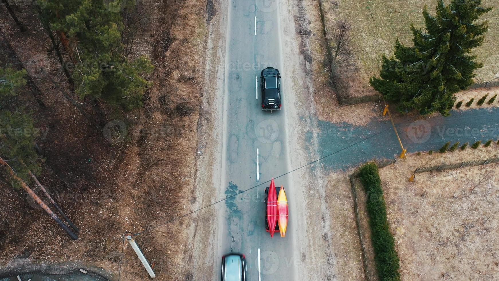 Several cars with kayaks on roof rack driving on the road among trees photo