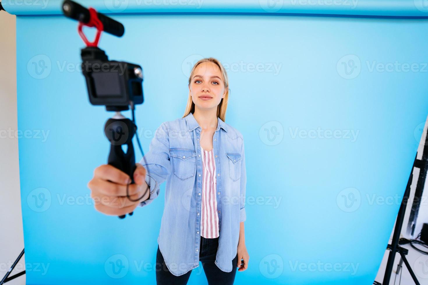 hermosa chica blogger hace sus necesidades en la cámara aislado fondo azul foto