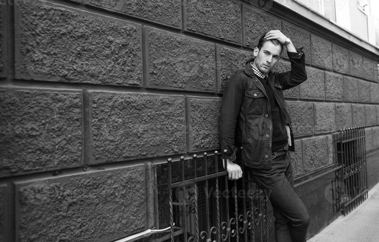 Male model in jeans on the background of a red wall photo