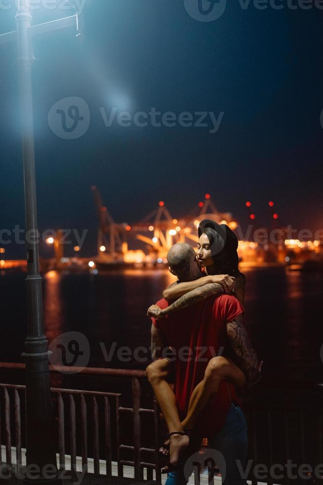 Guy and girl hugging each other on a background of the night port photo