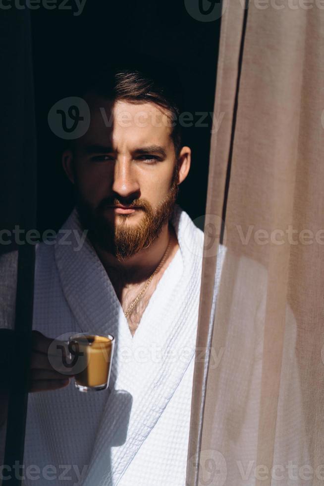 Male in white bathrobe with coffee mug in hand. photo