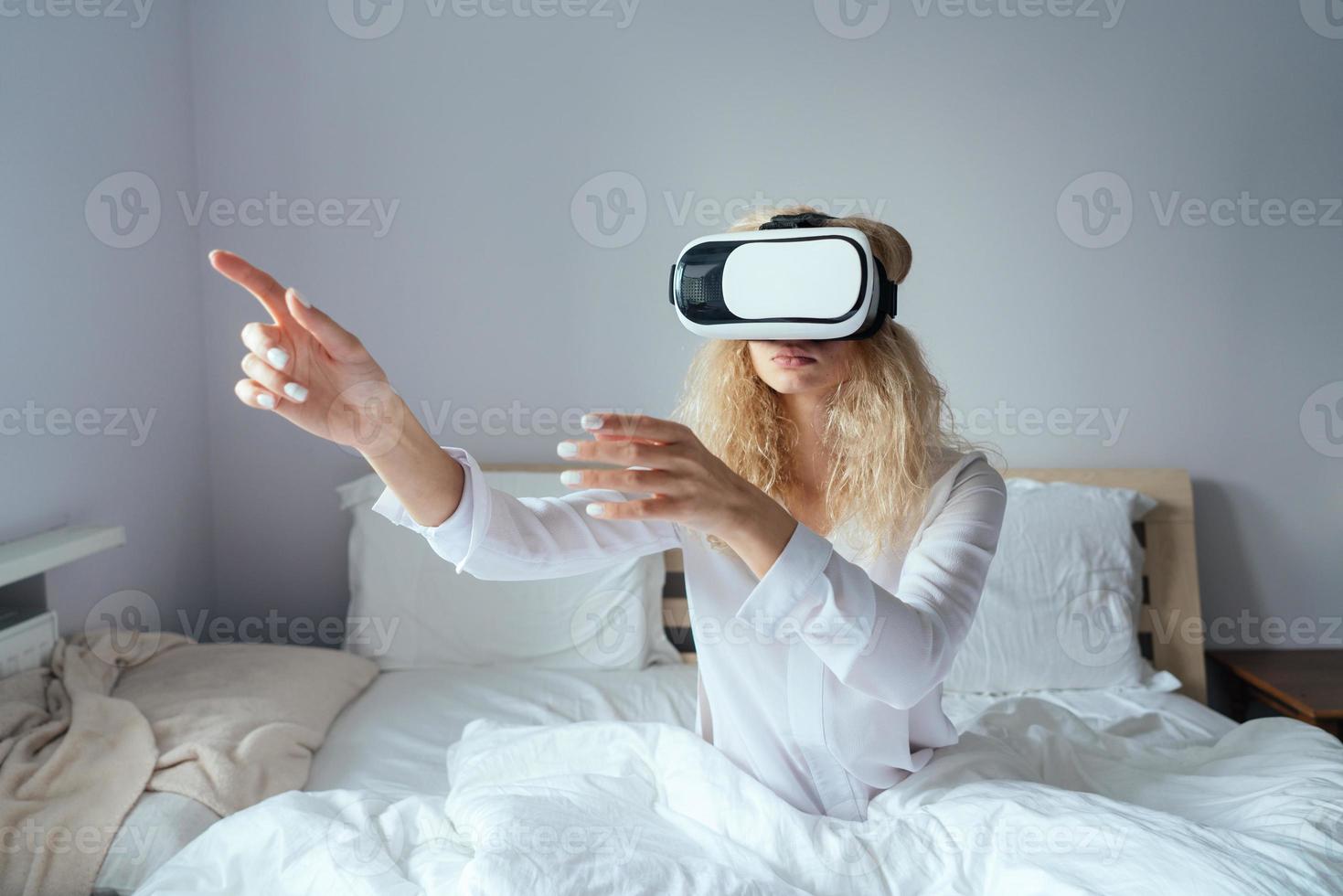 Girl sitting on a bed with VR headset photo