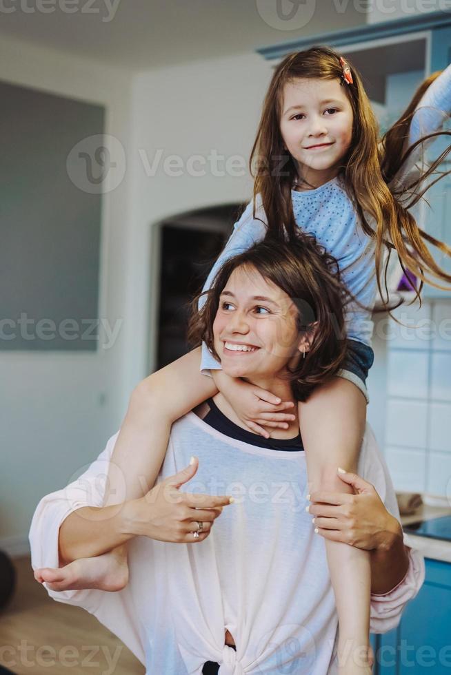 beautiful little daughter piggybacking on her happy mother photo