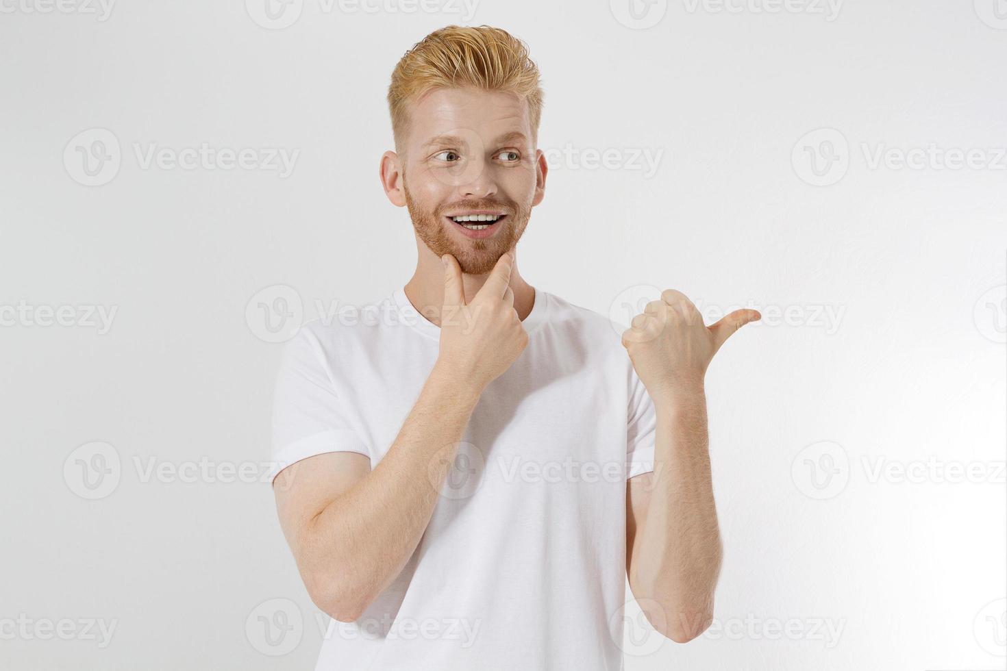 Happy young redhead guy, red stylish beard isolated. Man pointing copy space for advertising. Male in white t shirt, trend haircut. Successful young entrepreneur. Surprised shocked excited man face photo