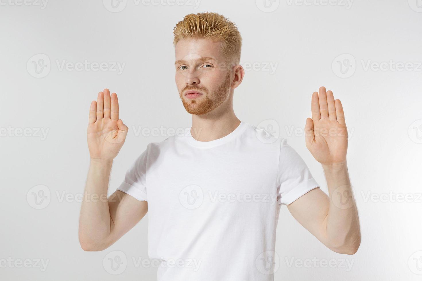 Stop hands sign. Young man in blank template white t shirt showing stop gesture. Redheaded and red beard guy isolated. hazard protection concept. Copy space and mock up on t-shirt. photo